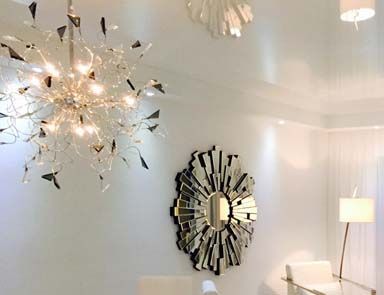 A living room with a chandelier and a mirror on the wall.