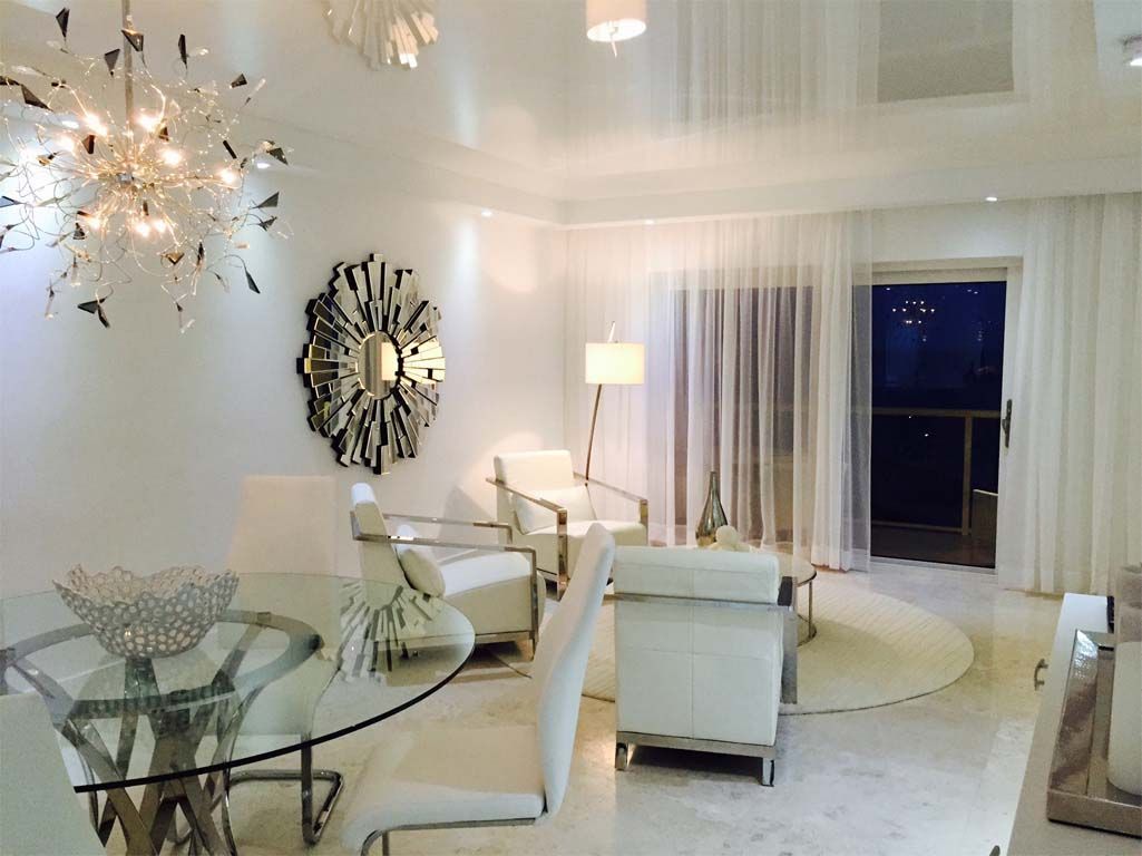 A living room with white furniture and a glass table