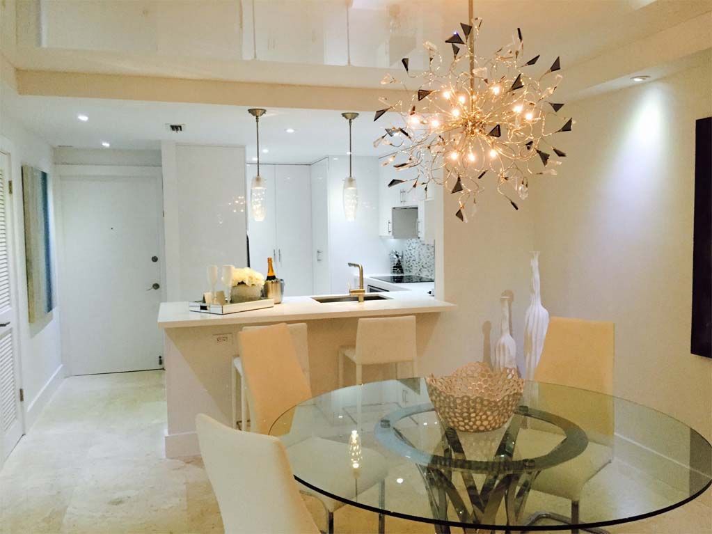 A dining room with a glass table and chairs and a chandelier