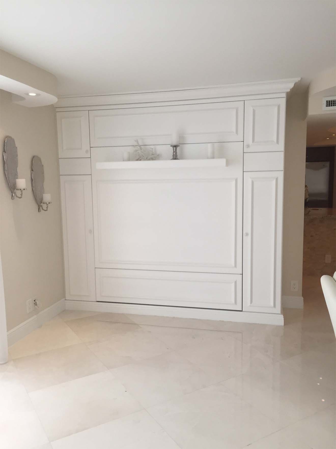 A living room with white cabinets and a wall mounted bed.