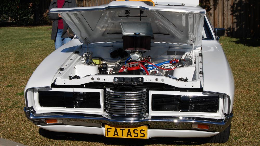 a white Ford classic muscle car with its hood popped