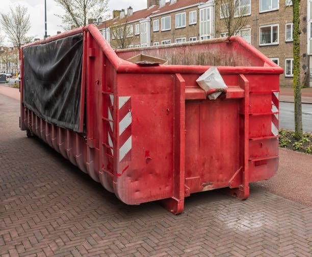 A large red dumpster is parked on the side of the road.