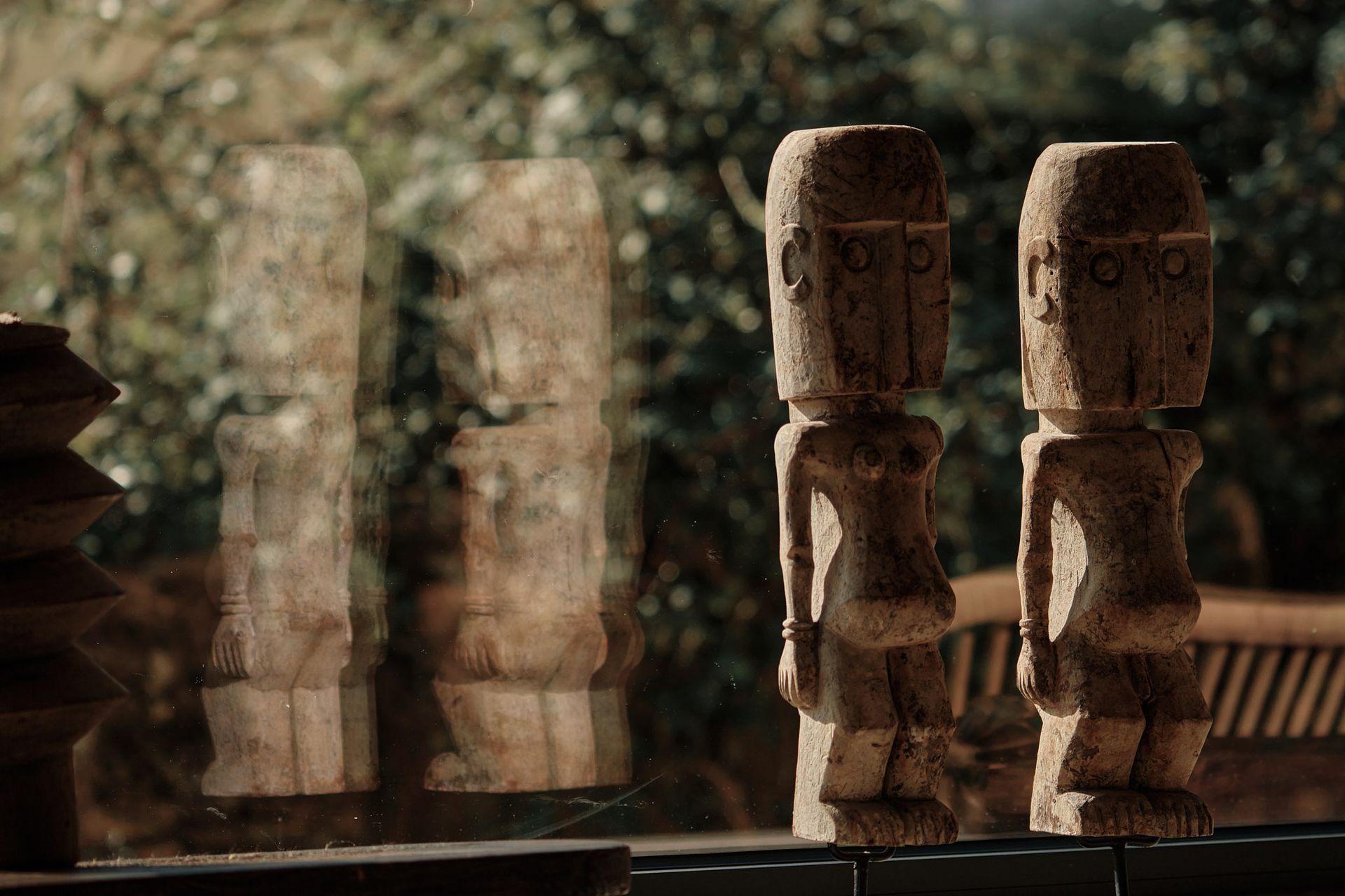 Two wooden statues are sitting next to each other on a table.