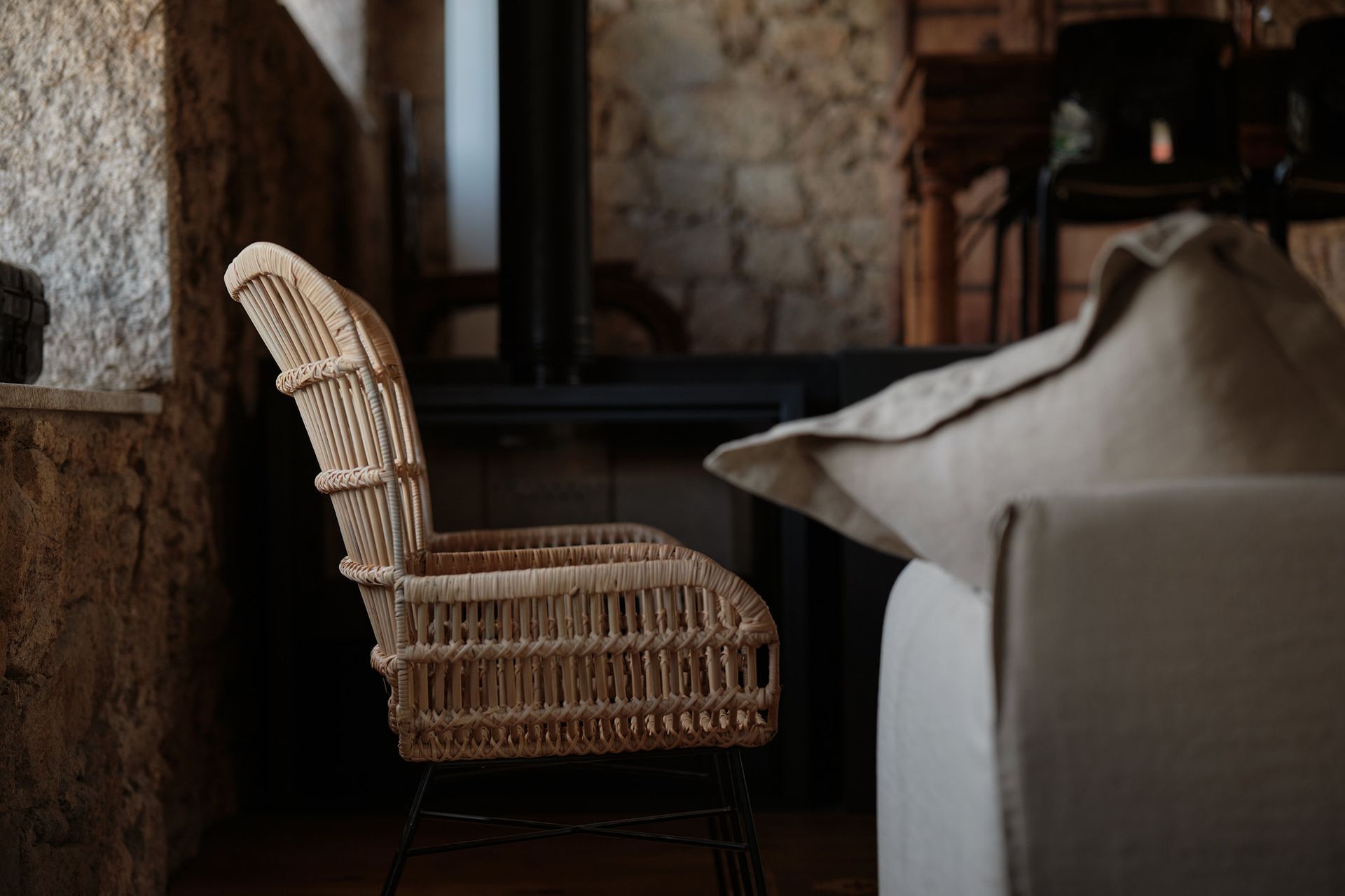 A wicker chair is sitting next to a couch in a living room.
