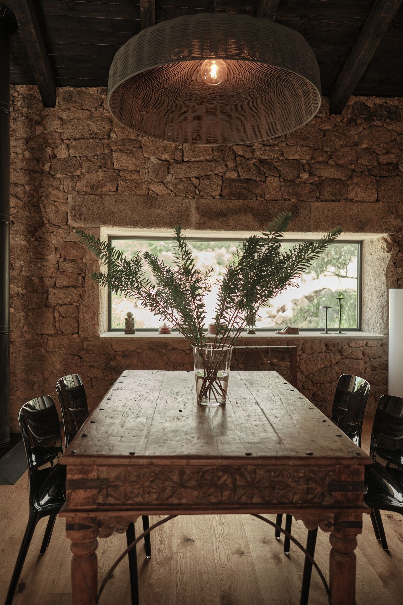 A wooden table with a vase of flowers on it in a dining room.