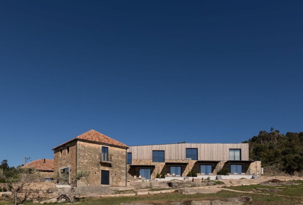 A large house is sitting on top of a hill in the middle of a field.
