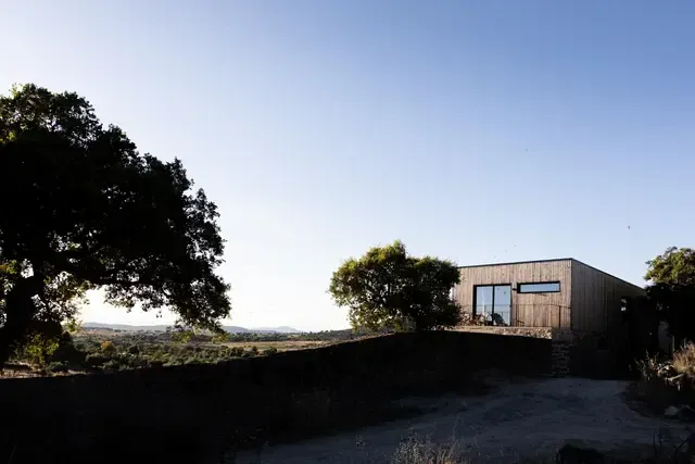 A house sitting on top of a hill with trees in front of it