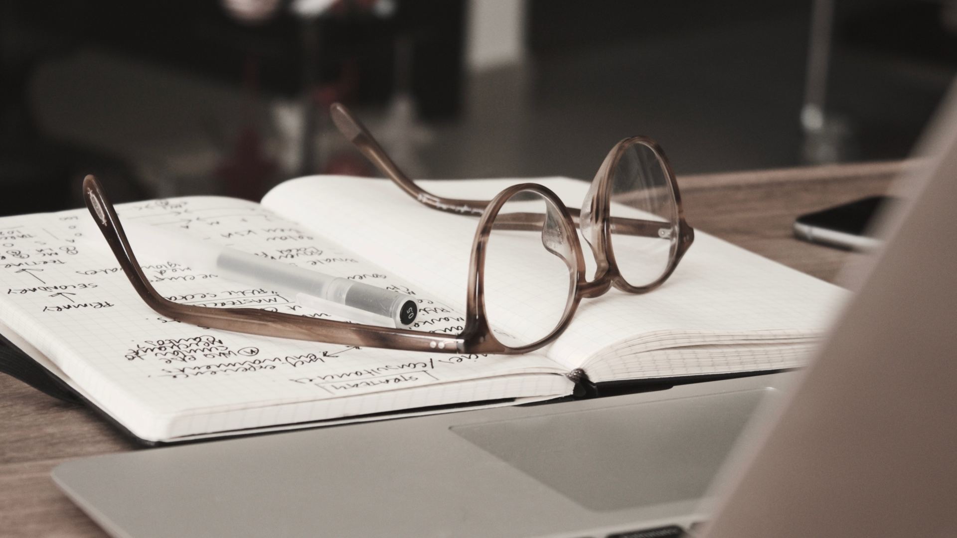photograph of an open book on a desk with a pair of spectacles on the top

