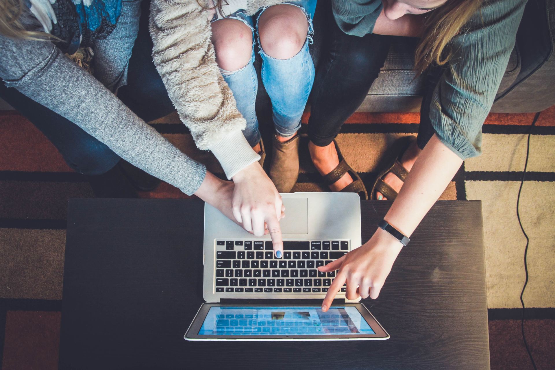 photo of a laptop with 3 people looking at the screen