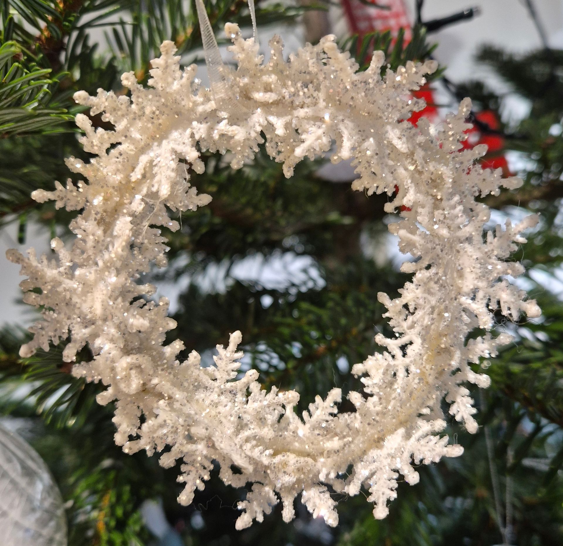 A white wreath Christmas decoration on a Christmas tree
