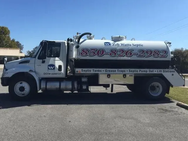 A white vacuum truck is parked in a parking lot.