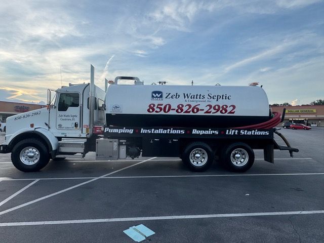 Septic truck with Zeb Watts Septic logo parked in a lot. White truck with black tank, phone number visible.