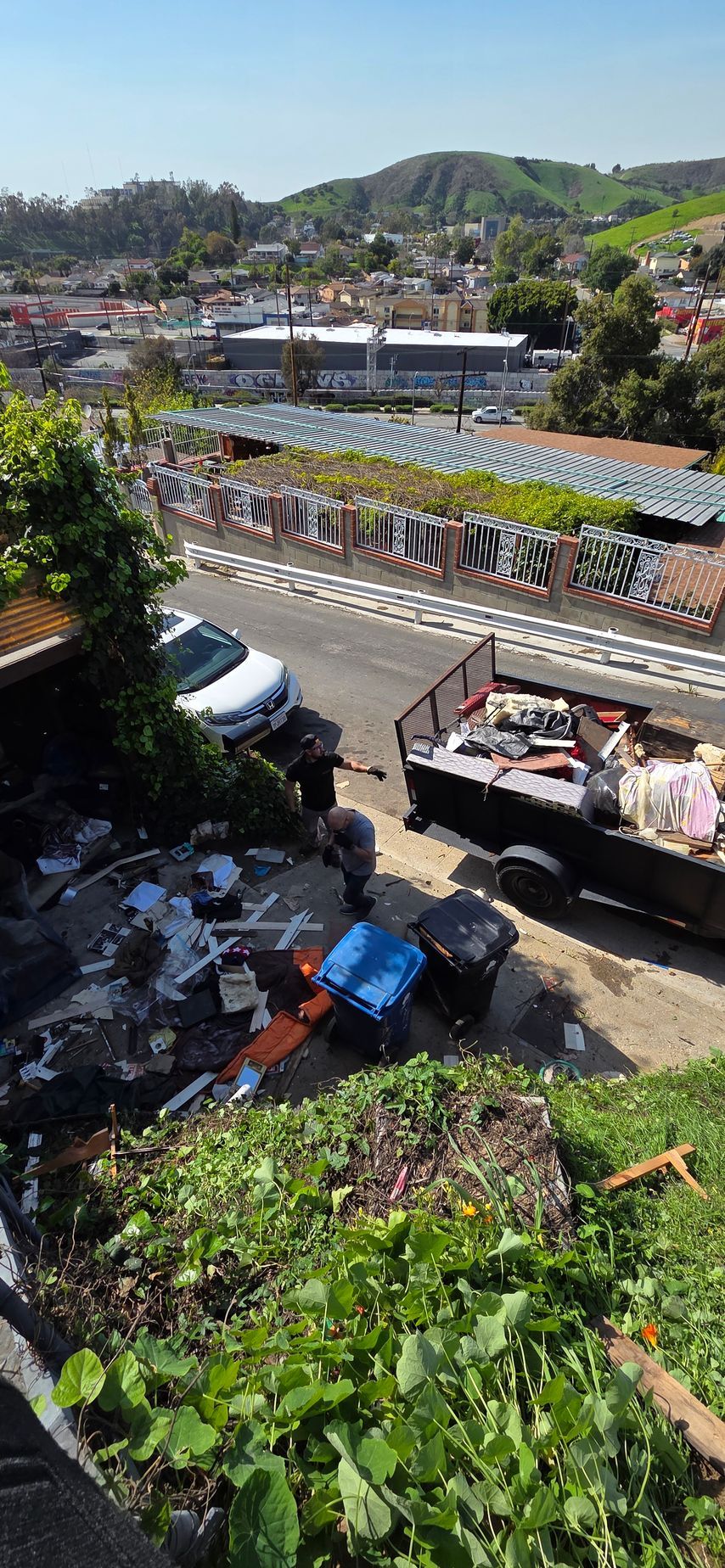A truck with a trailer full of junk is parked on the side of the road.