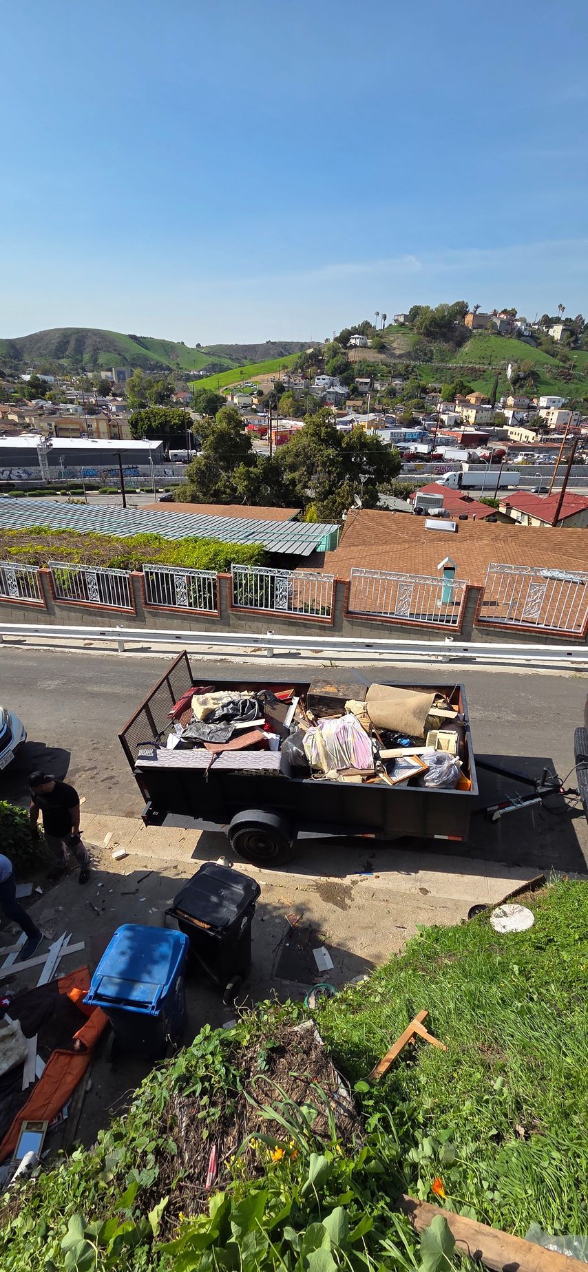 A dumpster filled with junk is parked on the side of the road.