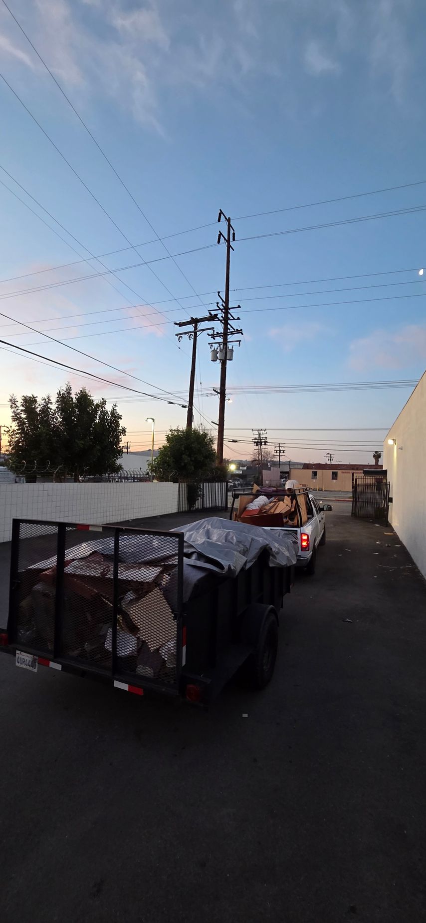 A row of trucks are parked in a parking lot next to a building.
