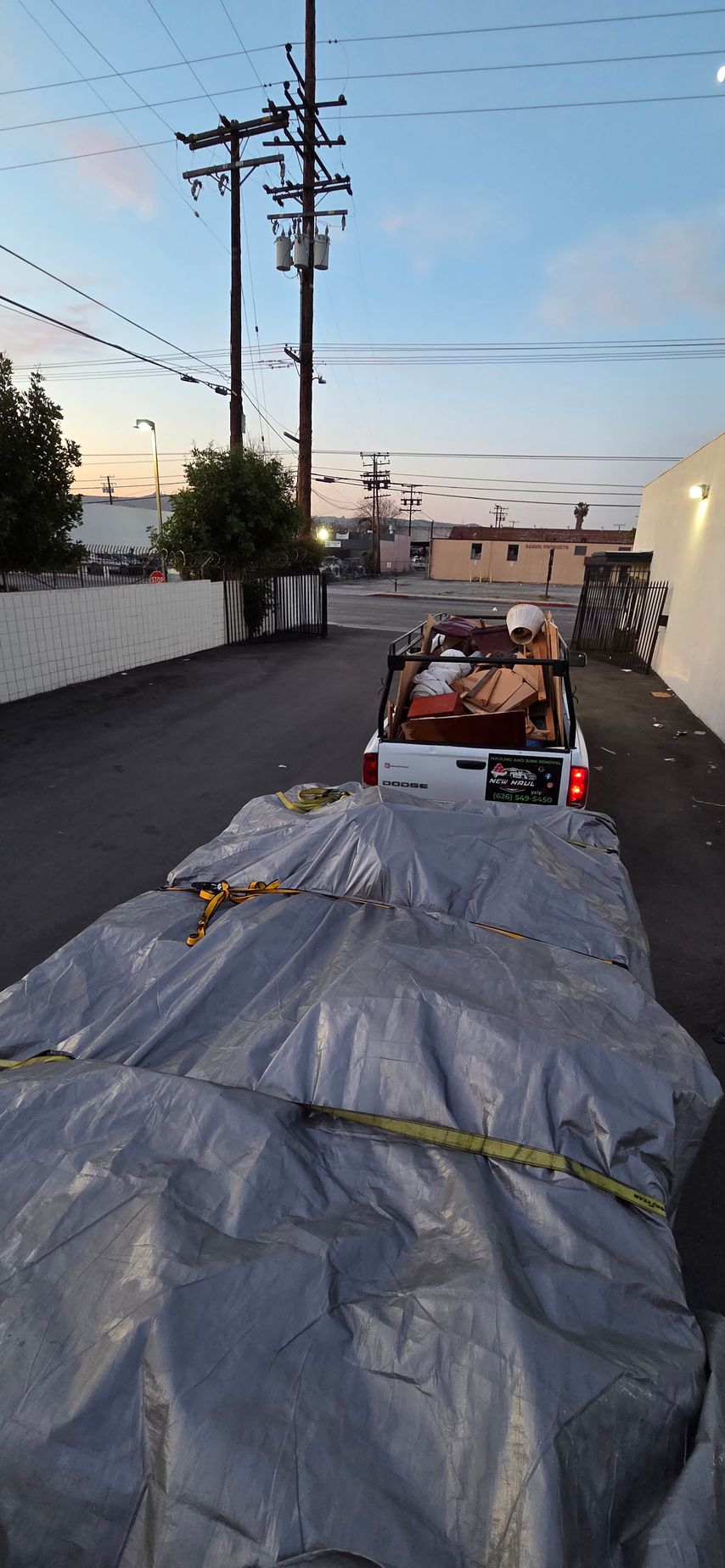 A truck with a tarp on the back of it is parked on the side of the road.