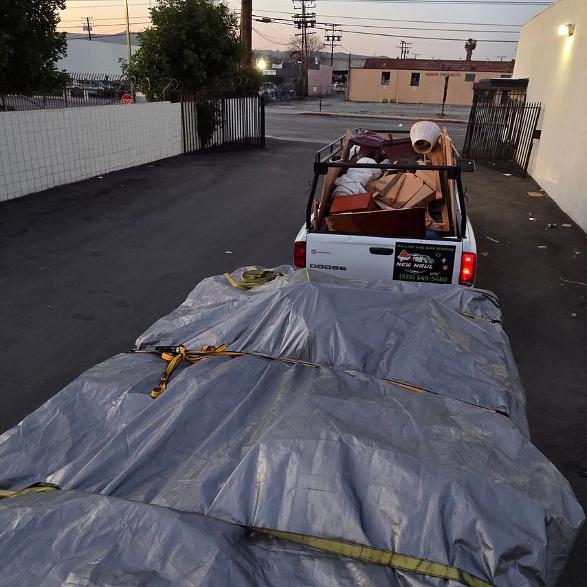 A truck with a tarp on the back of it is parked on the side of the road.