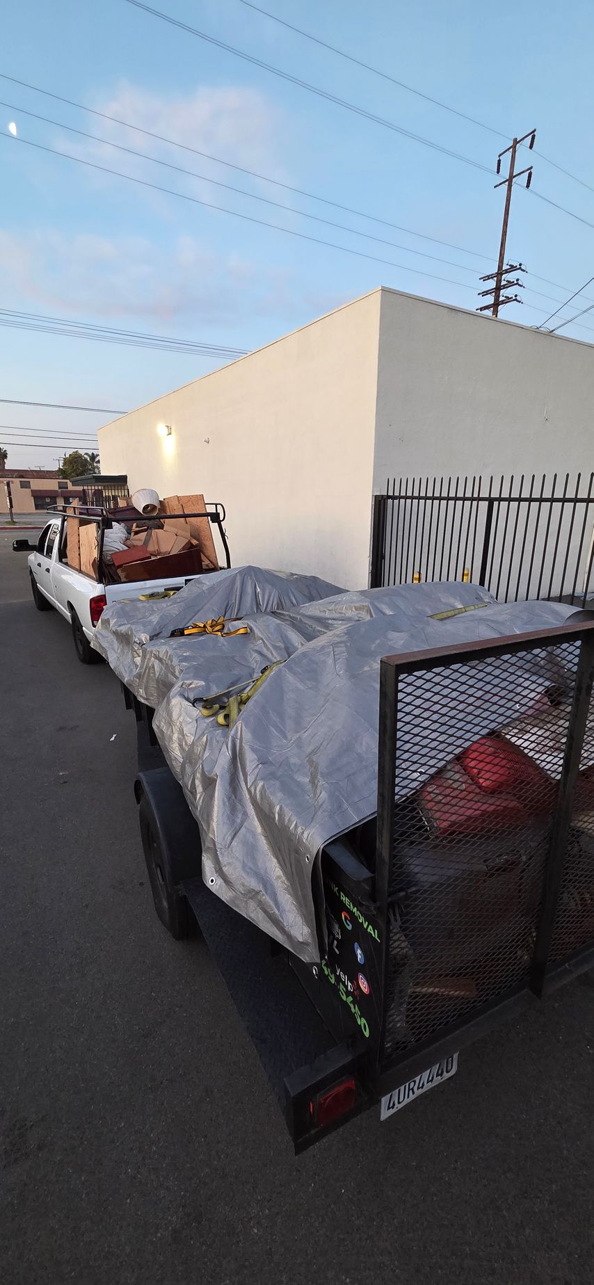 A truck with a trailer is parked in front of a building.