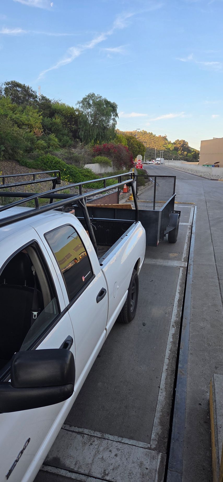A white truck is parked next to a trailer in a parking lot.