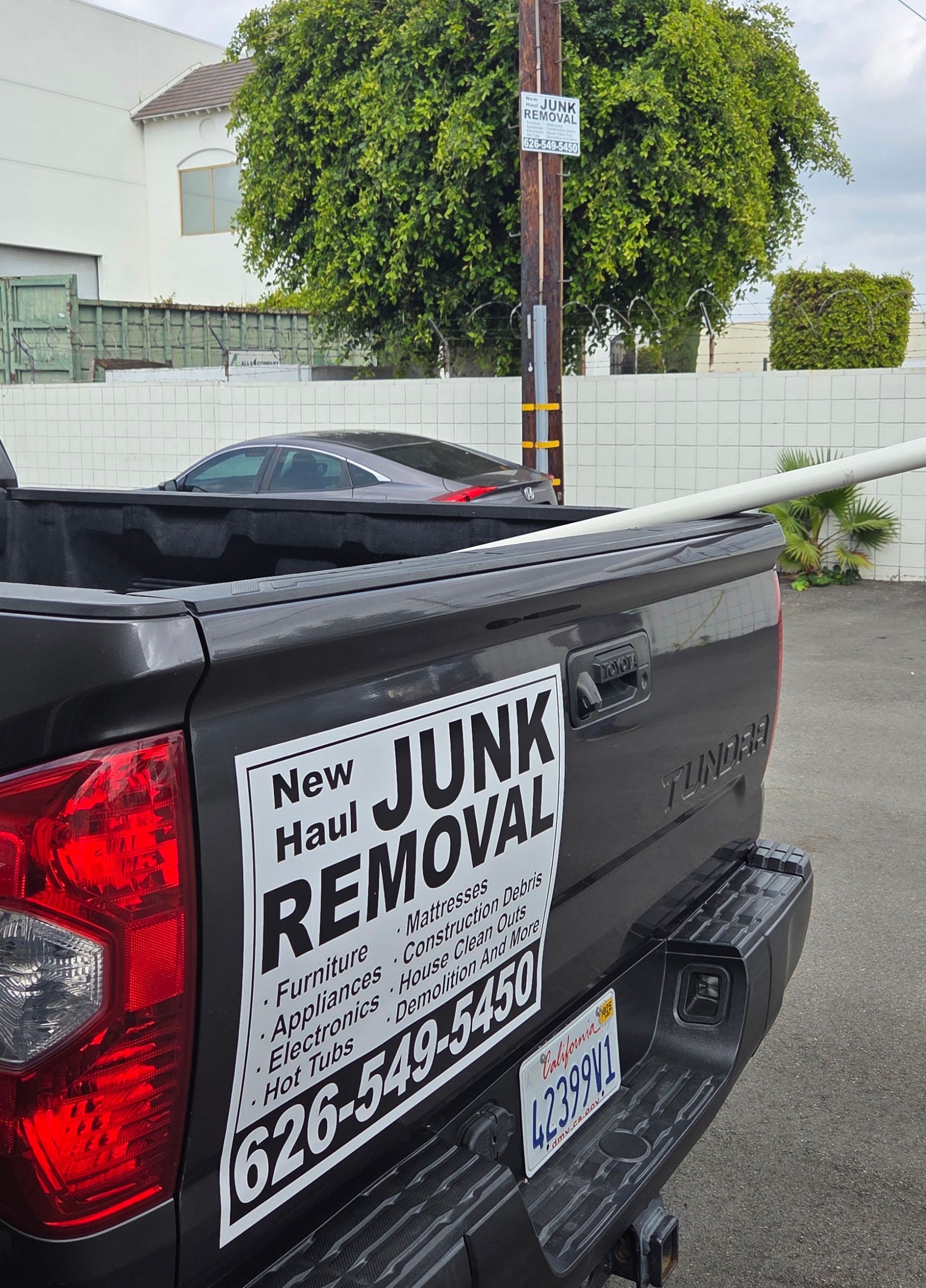 A truck is parked in a dirt lot next to a tree.