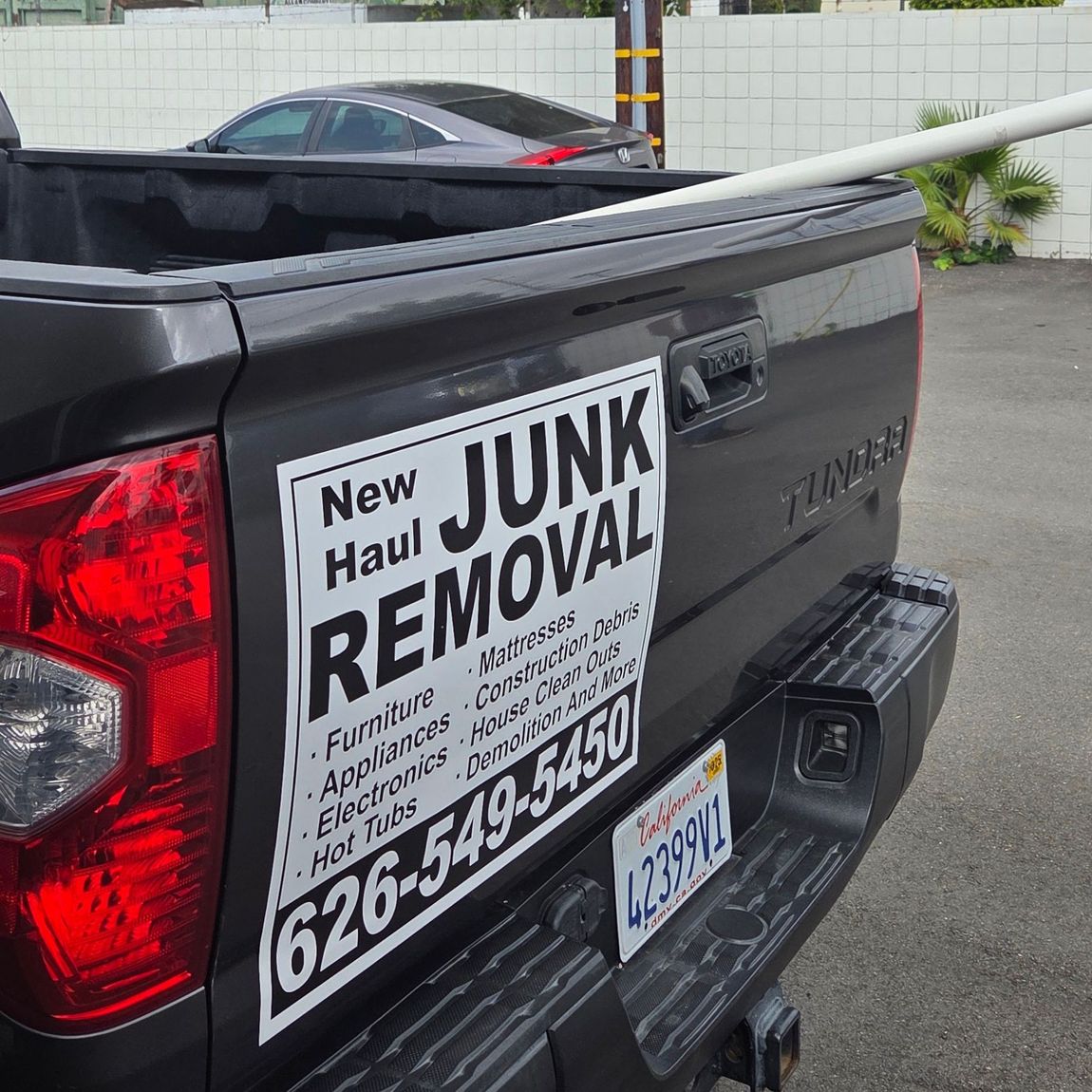 A black truck with a sign on the back that says junk removal