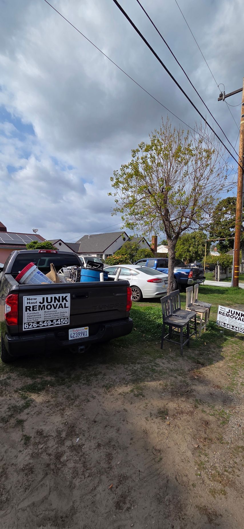 A truck is parked in a dirt lot next to a tree.