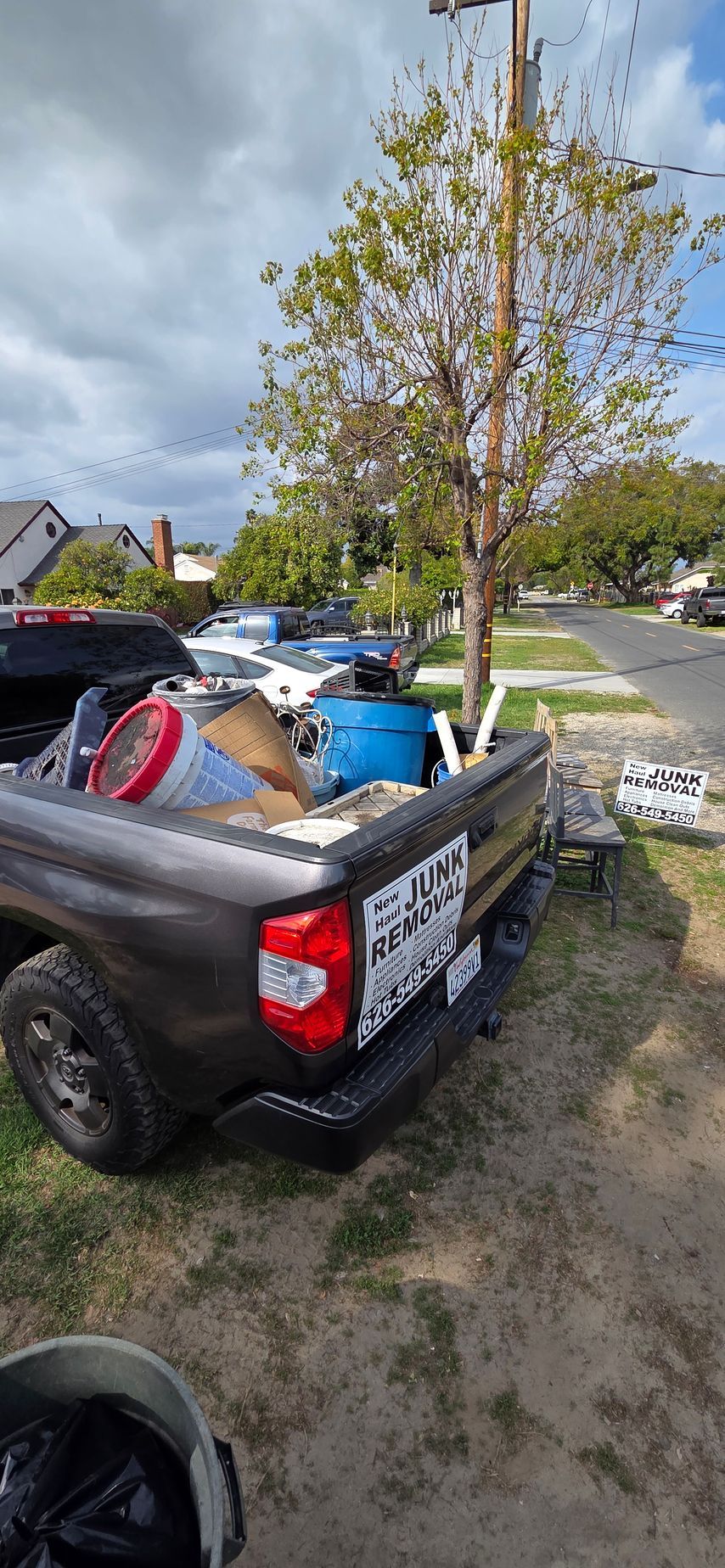 A truck filled with junk is parked on the side of the road.