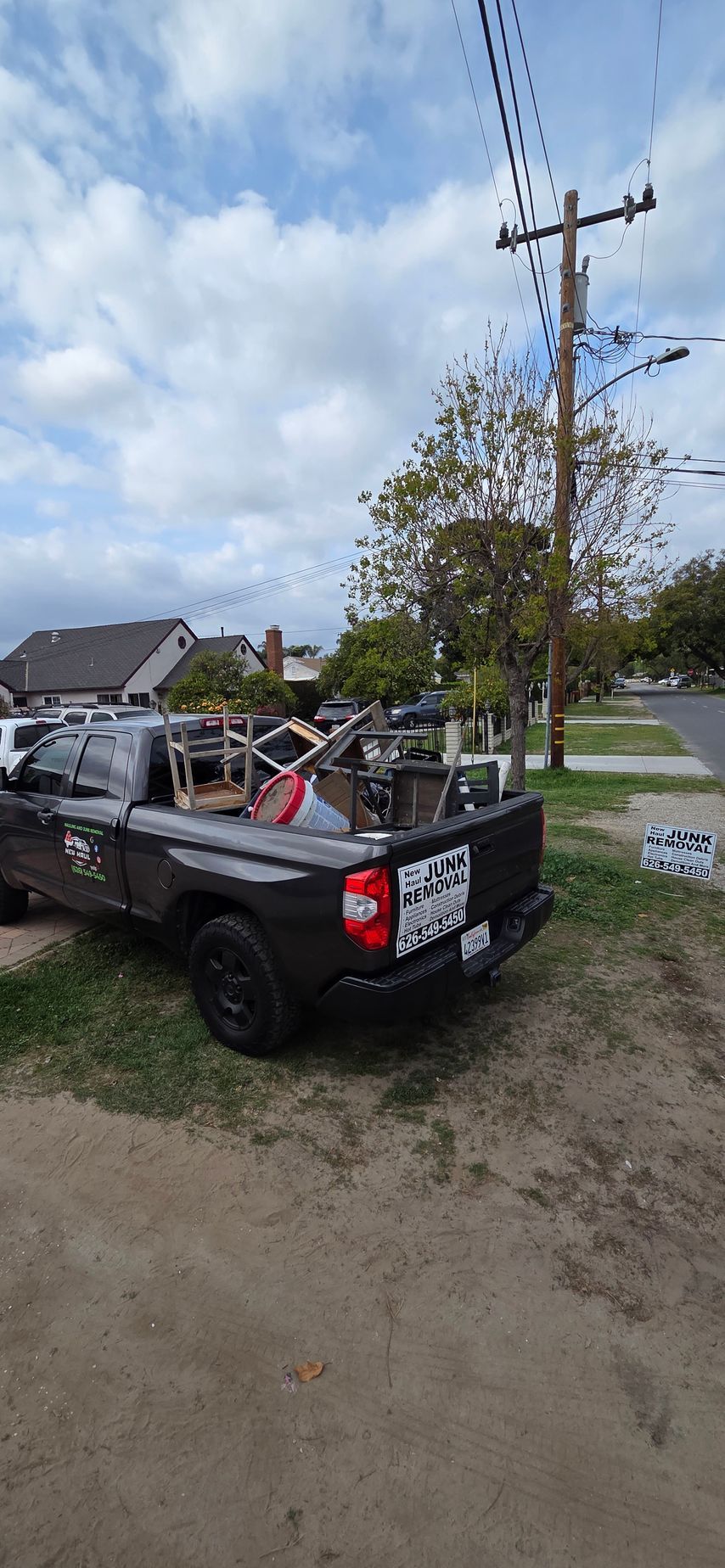 A black truck is parked in a dirt lot next to a power pole.