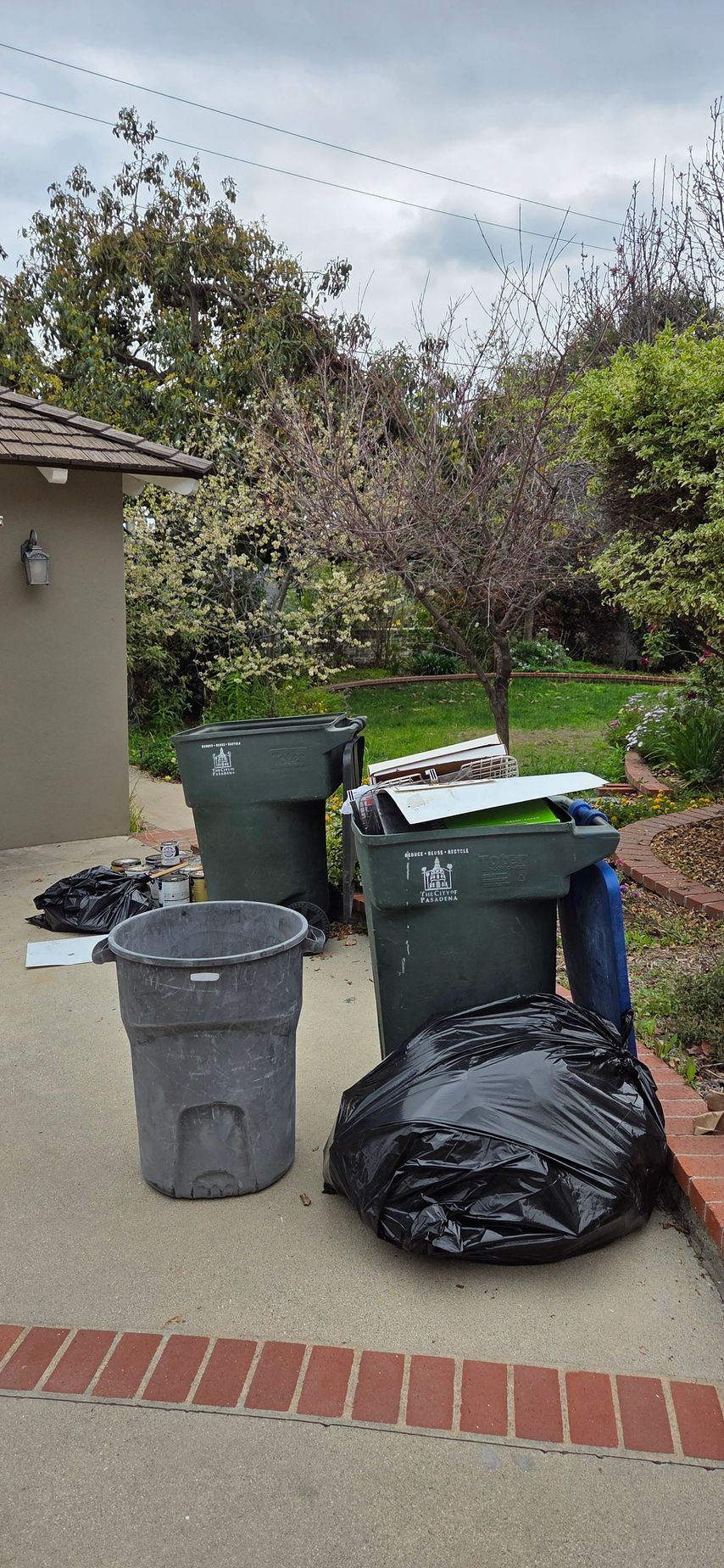A couple of trash cans sitting on top of a concrete patio.