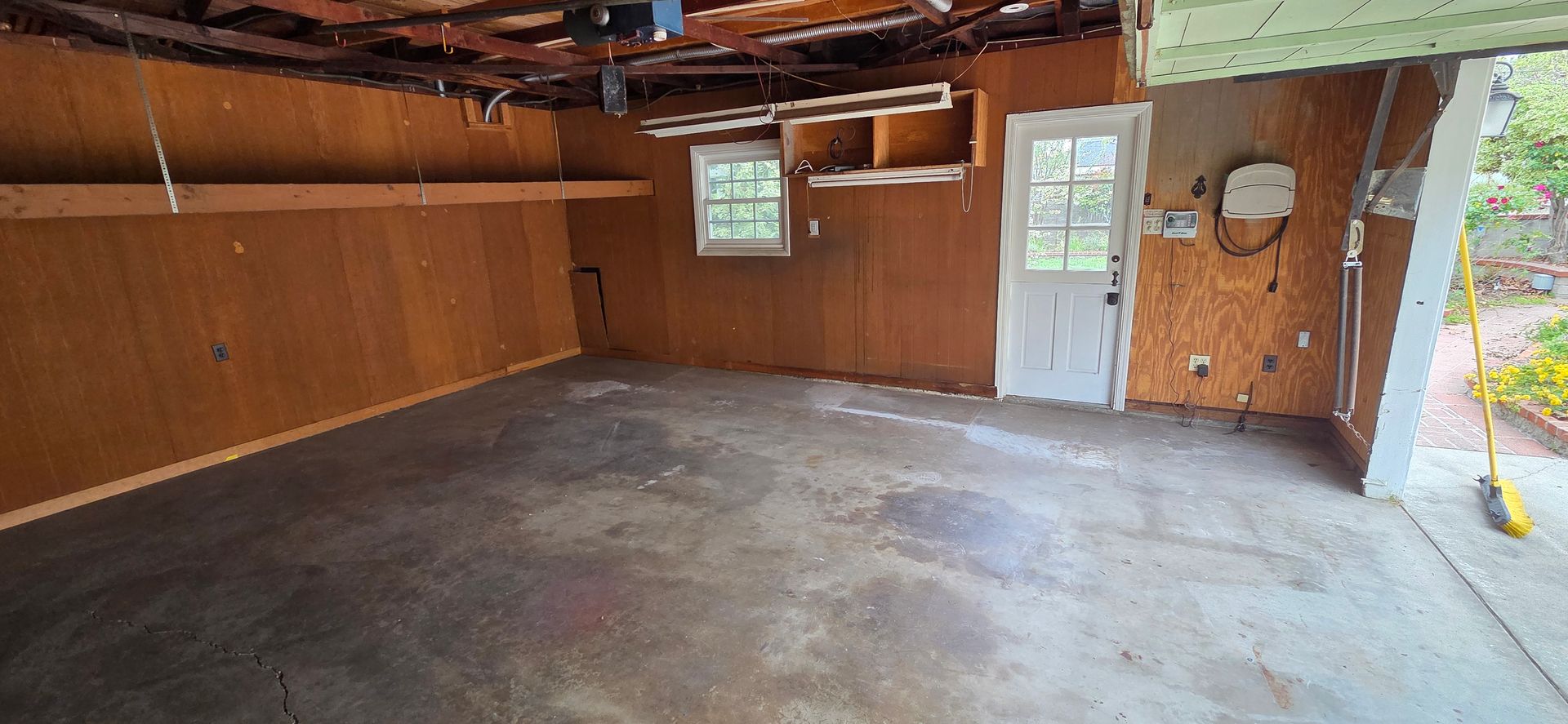 An empty garage with a concrete floor and wooden walls.