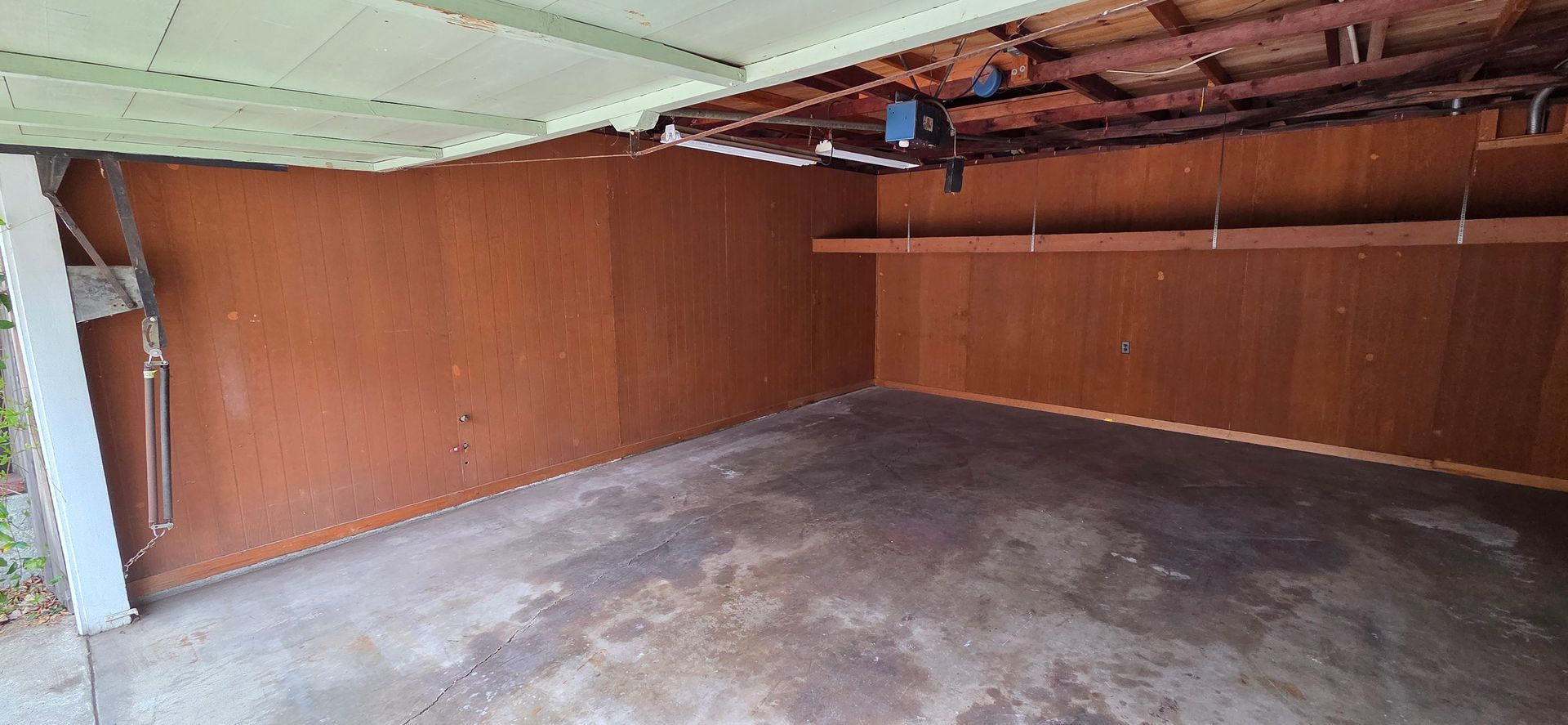 An empty garage with a wooden wall and concrete floor.