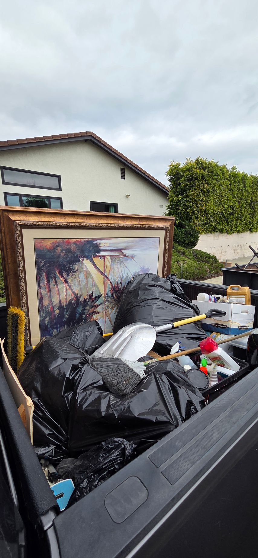 A truck filled with trash and a painting in the back.