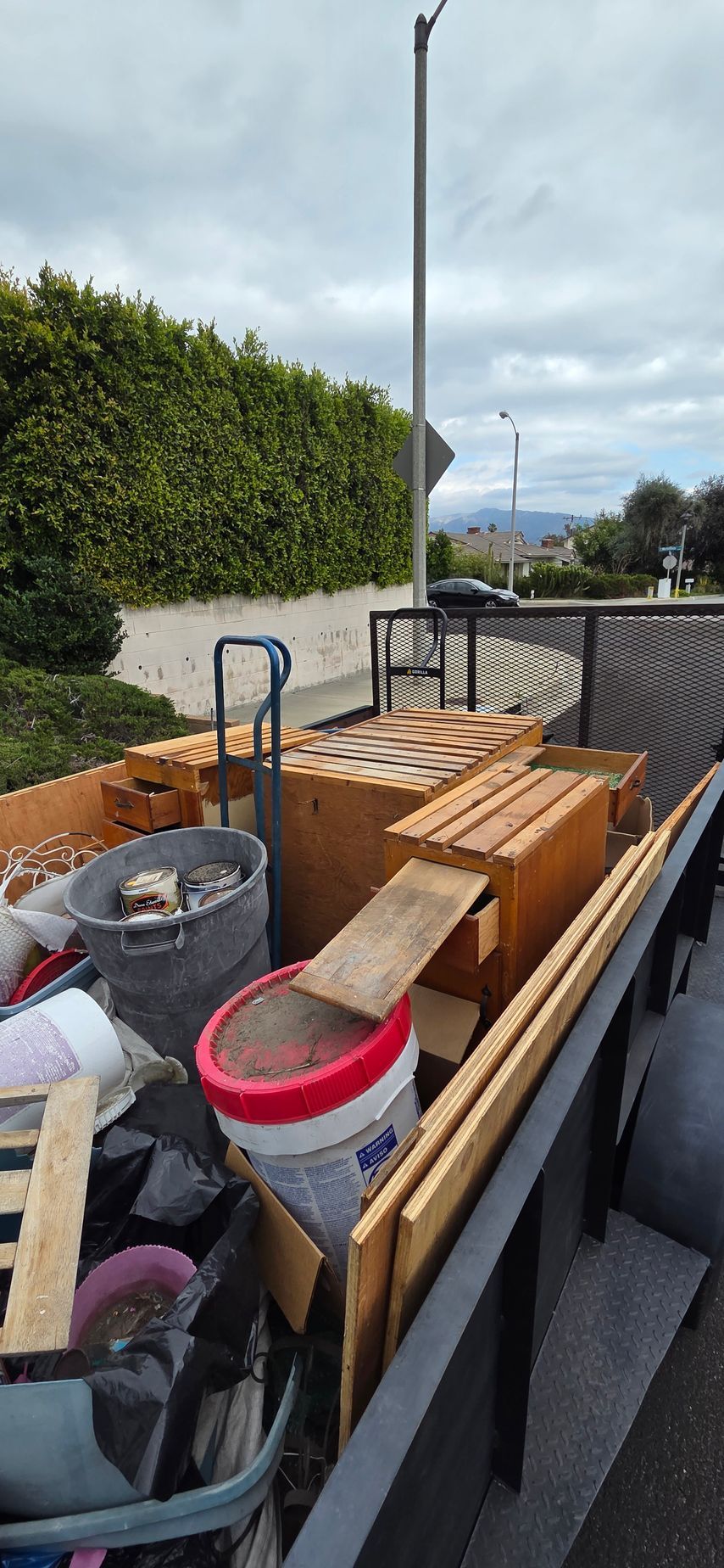 A trailer filled with lots of junk is parked on the side of the road.