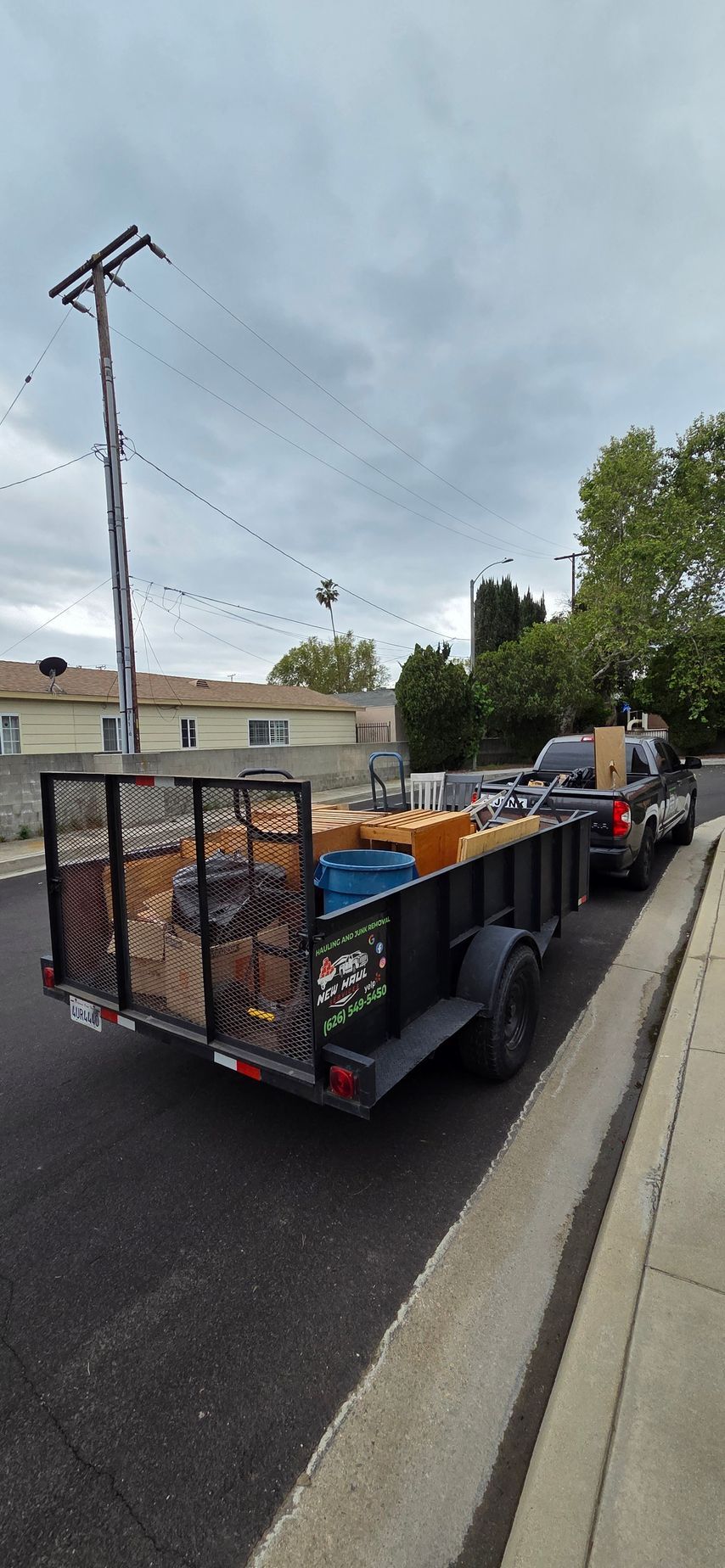A trailer is parked on the side of the road next to a truck.