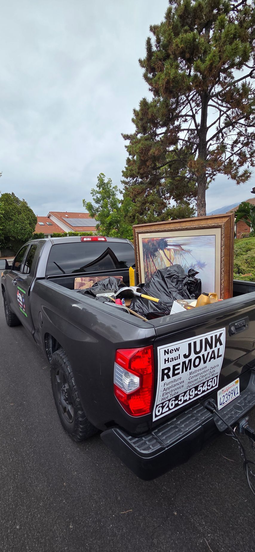 A black truck filled with junk is parked on the side of the road.