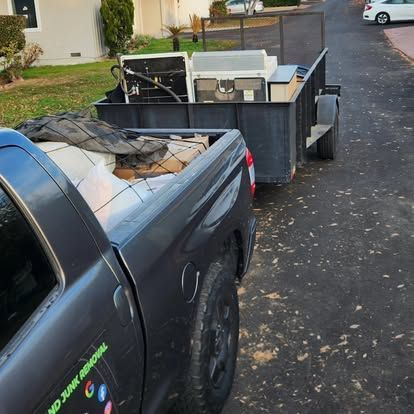 A truck with a trailer full of junk is parked on the side of the road.
