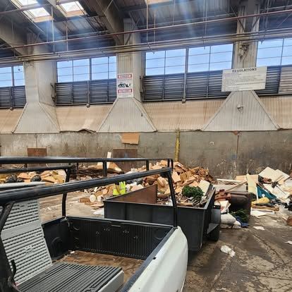 A white truck is parked in a warehouse filled with garbage.