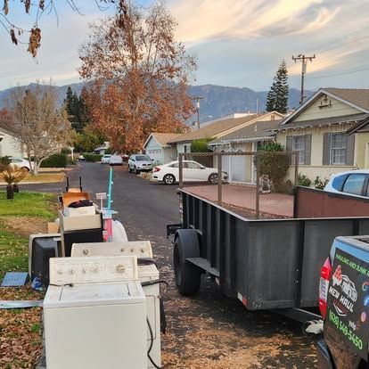 A truck with a trailer full of appliances is parked in front of a house