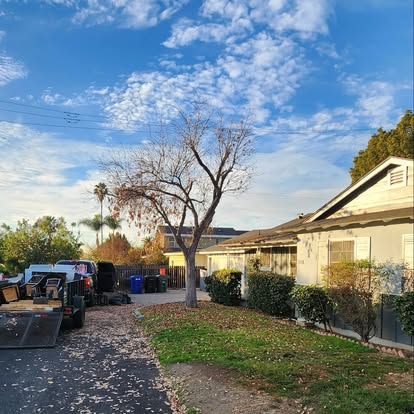 A truck is parked in front of a house with a tree in the background.