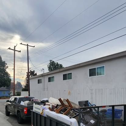 A truck is parked next to a dumpster filled with junk.