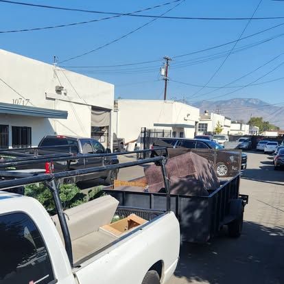 A white truck with a trailer in the back is parked in front of a building.