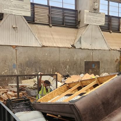 A man wearing a safety vest is standing in front of a pile of furniture
