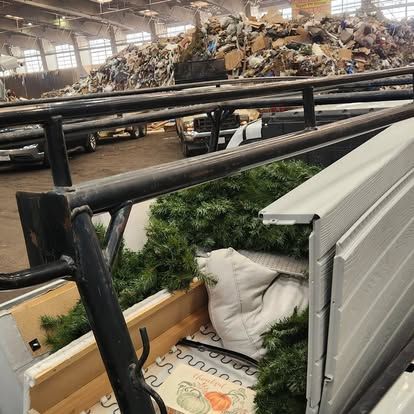 A christmas tree is sitting in the back of a truck in a warehouse.