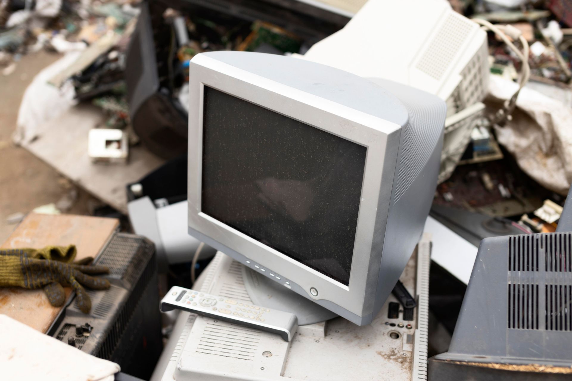 A computer monitor is sitting on top of a pile of electronics.