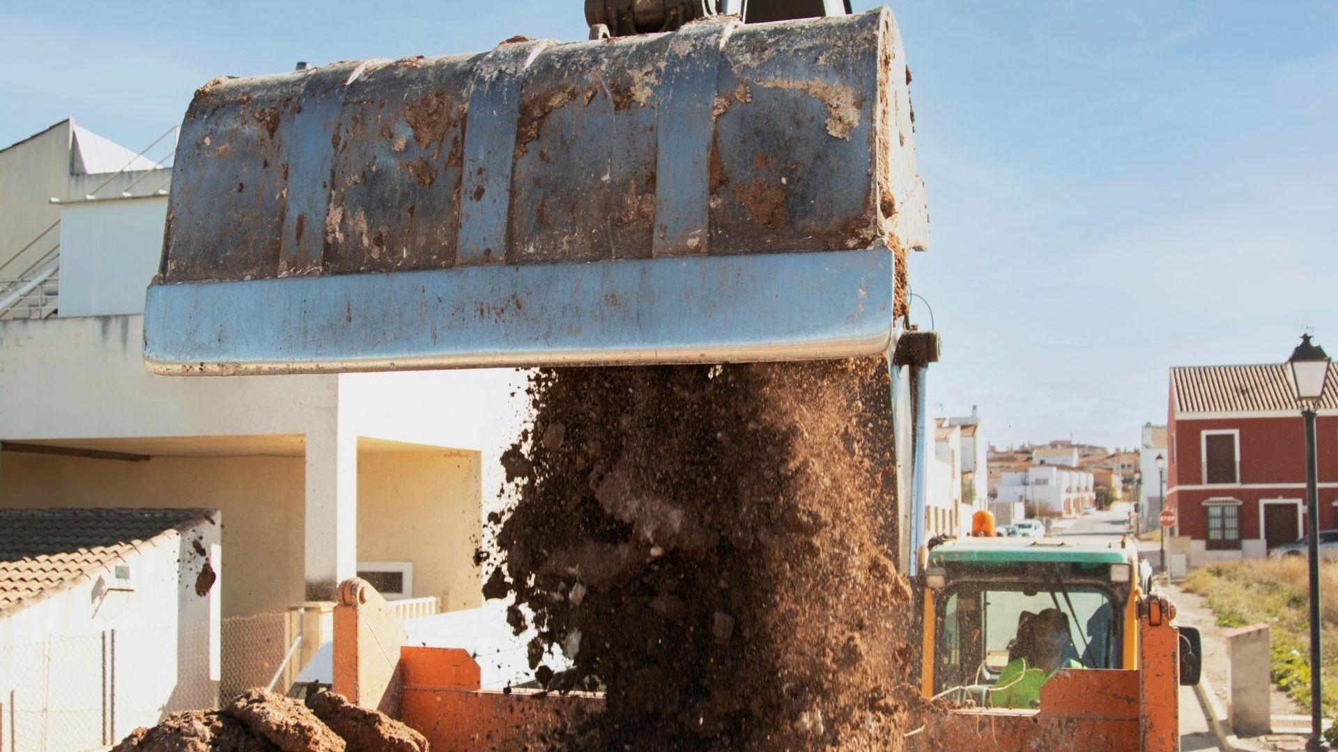 A bulldozer is loading dirt into a truck.