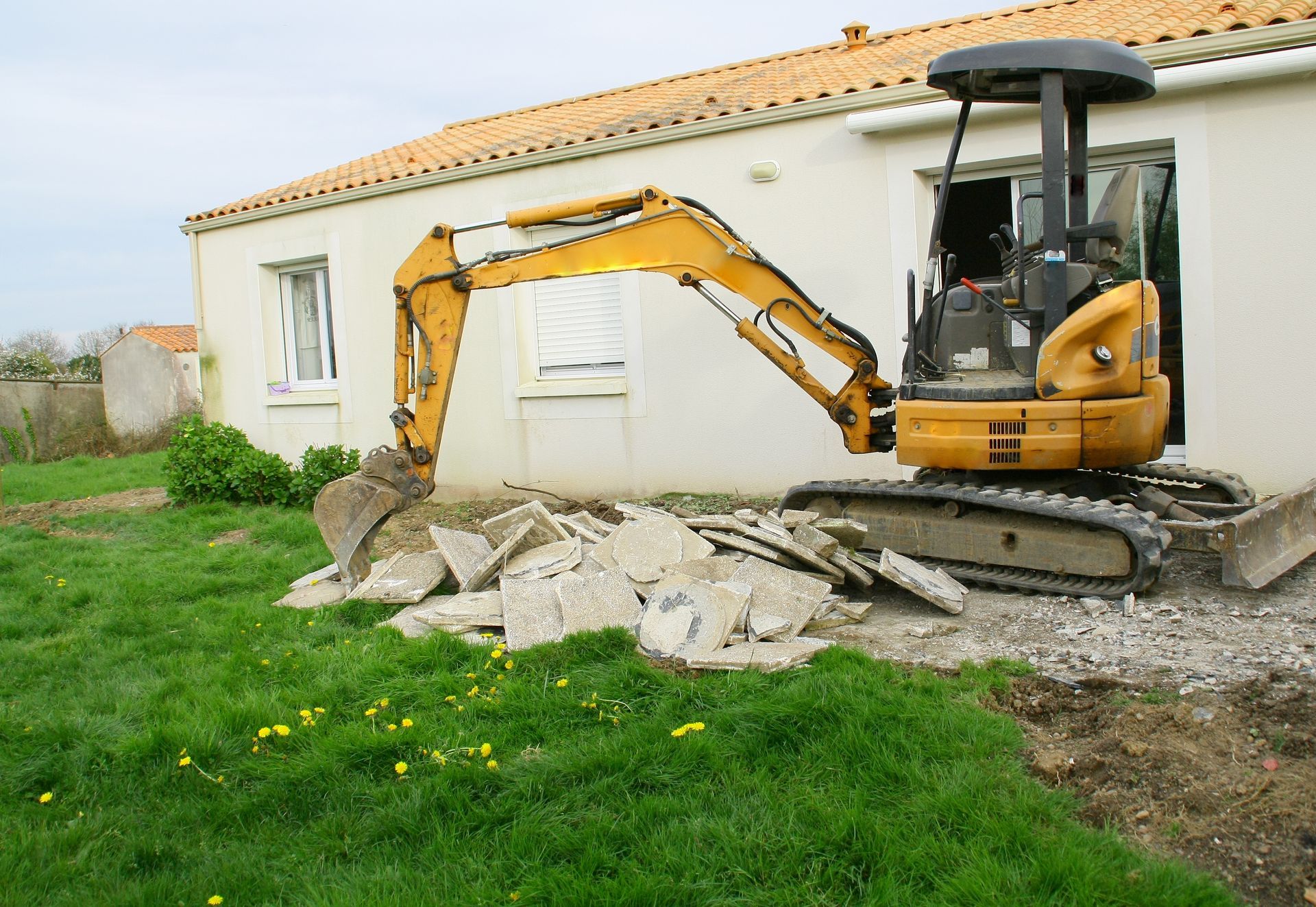 A large pile of concrete is being demolished by a crane.