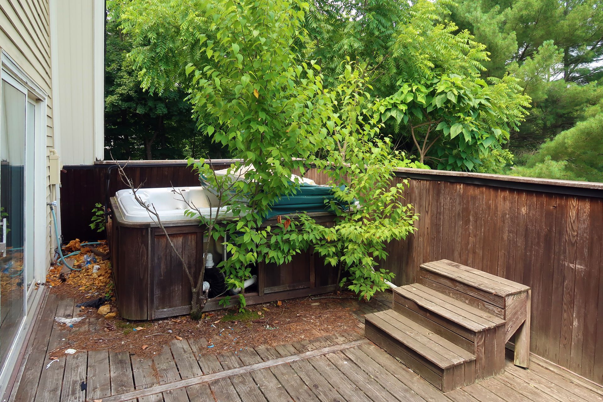 A hot tub is sitting on top of a wooden deck surrounded by trees.