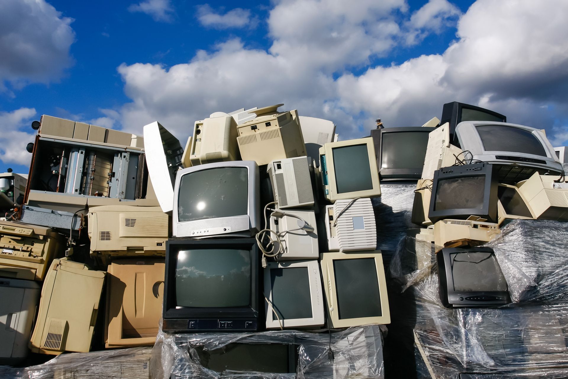 A computer monitor is sitting on top of a pile of electronics.