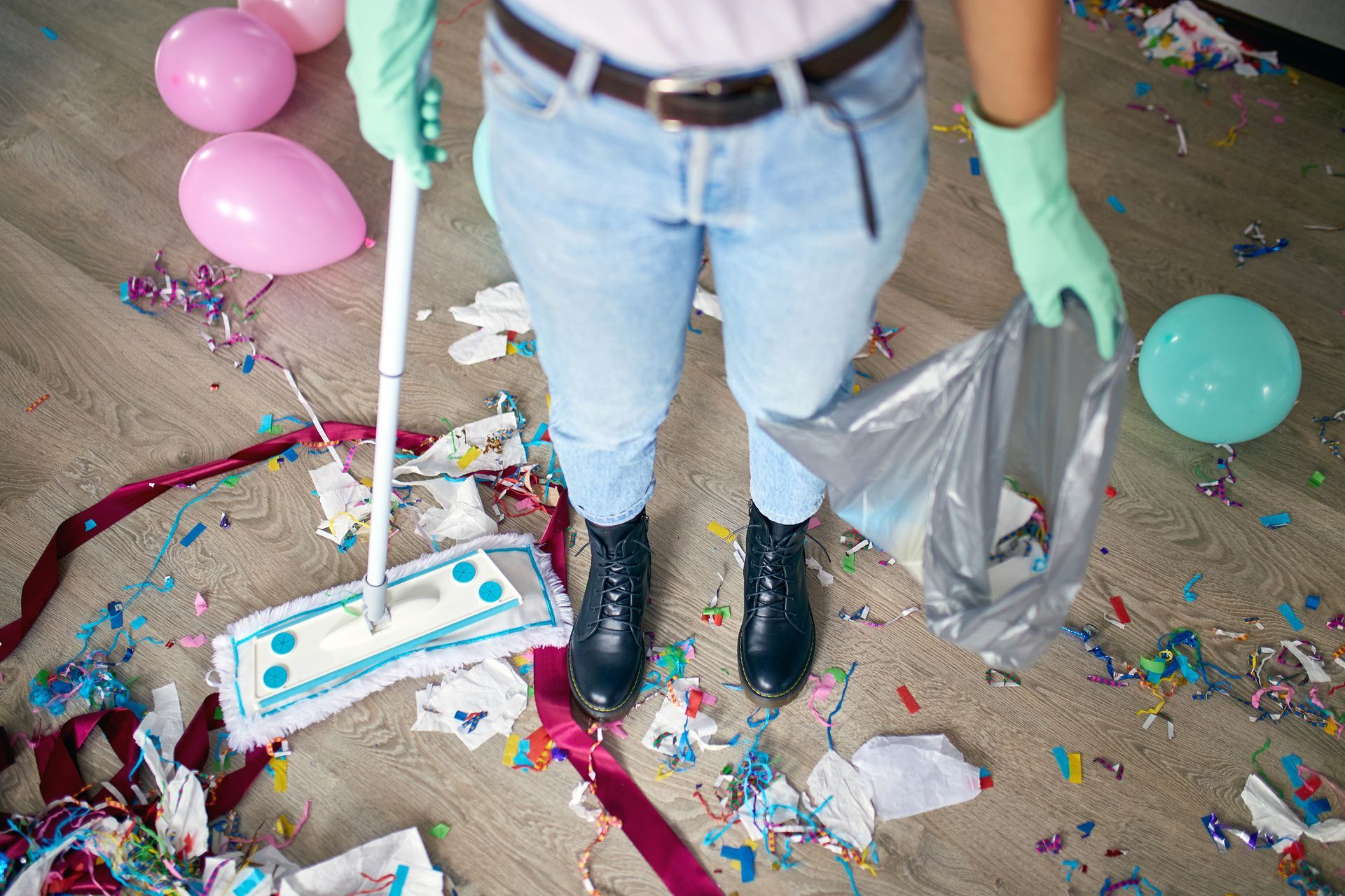 A person is standing on a messy floor holding a mop.