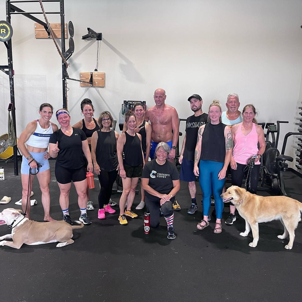 A group of people and a dog are posing for a picture in a gym.